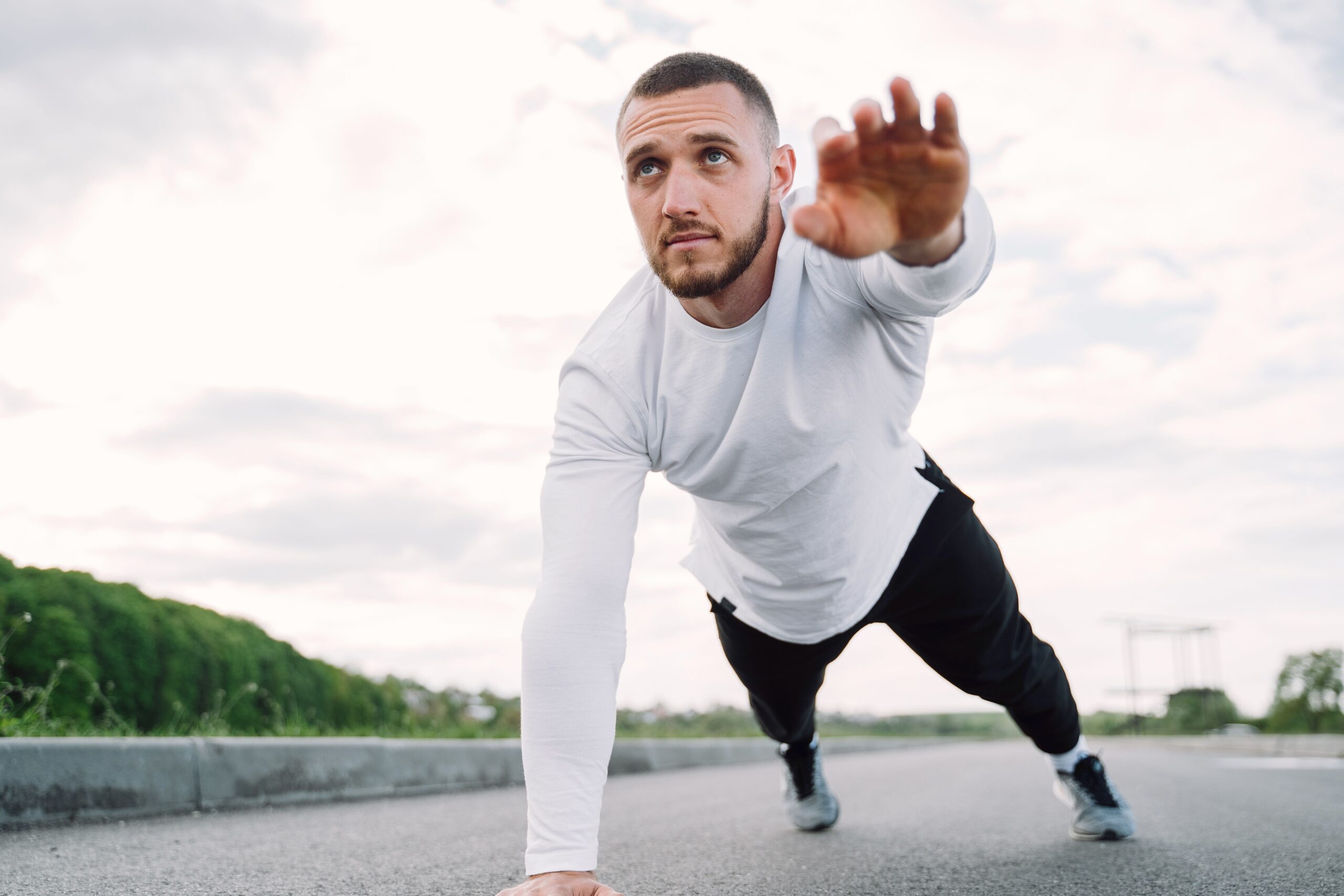 Man performing a one-arm plank exercise outdoors to improve strength, balance, and core stability